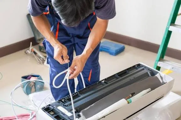 Technician servicing the tubing and components of a residential air conditioner