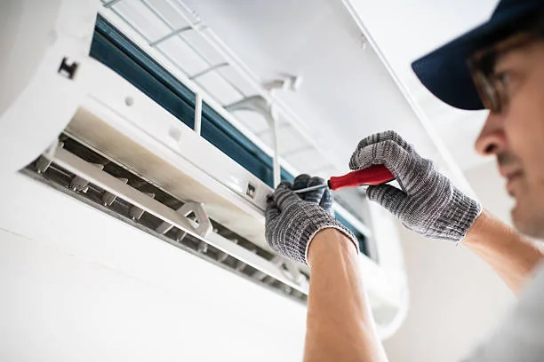 Technician cleaning an indoor air conditioning unit to support airflow