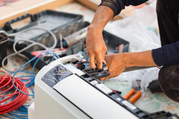 Technician working on the internal controls and airflow components of an air conditioner