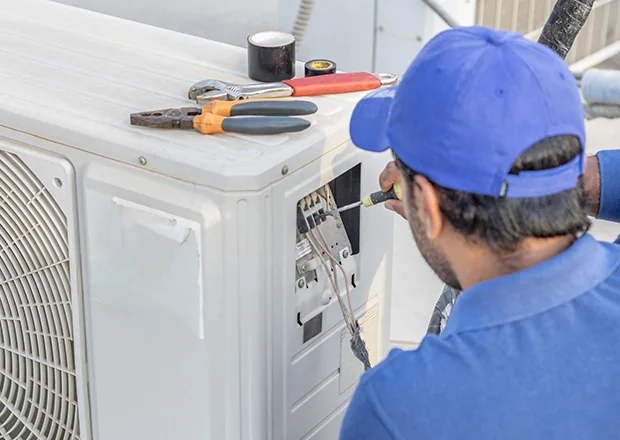 Technician testing an outdoor HVAC system during an urgent service call