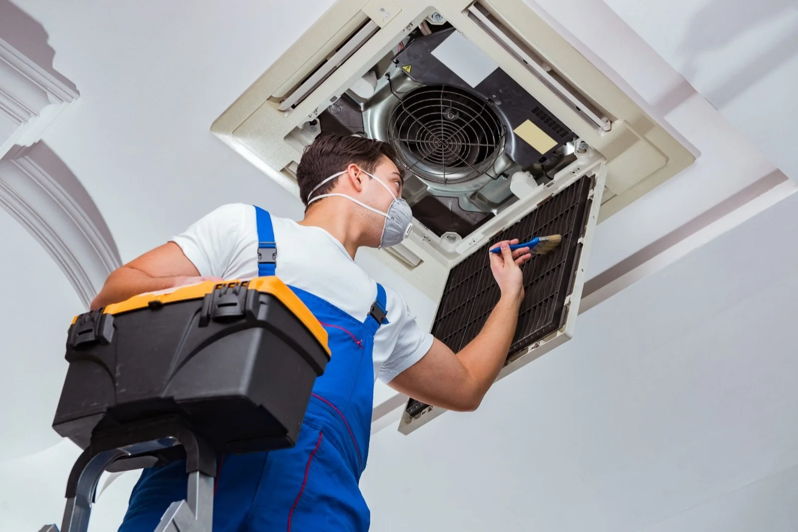 HVAC technician servicing a ceiling-mounted residential air conditioning system