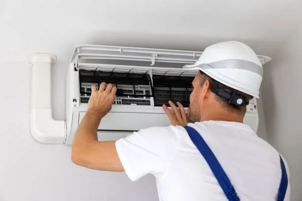 HVAC installer adjusting a wall-mounted air conditioning unit